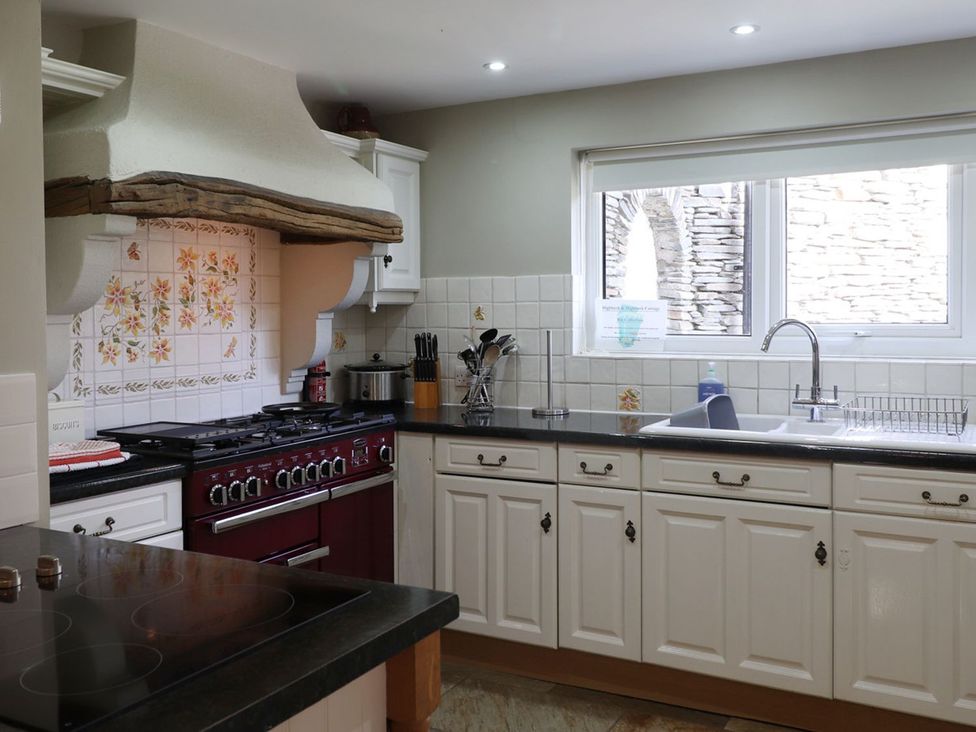 A kitchen with a stove, sink, and cabinets at High Beck in Kendal