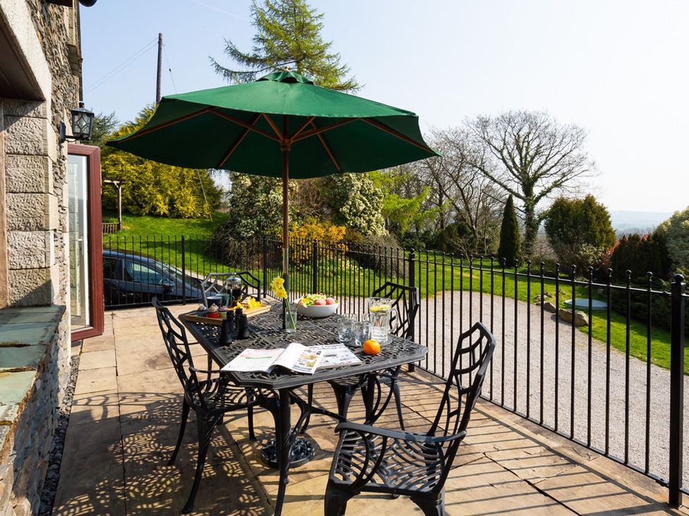 A patio with a table and chairs under an umbrella at High Beck in Kendal