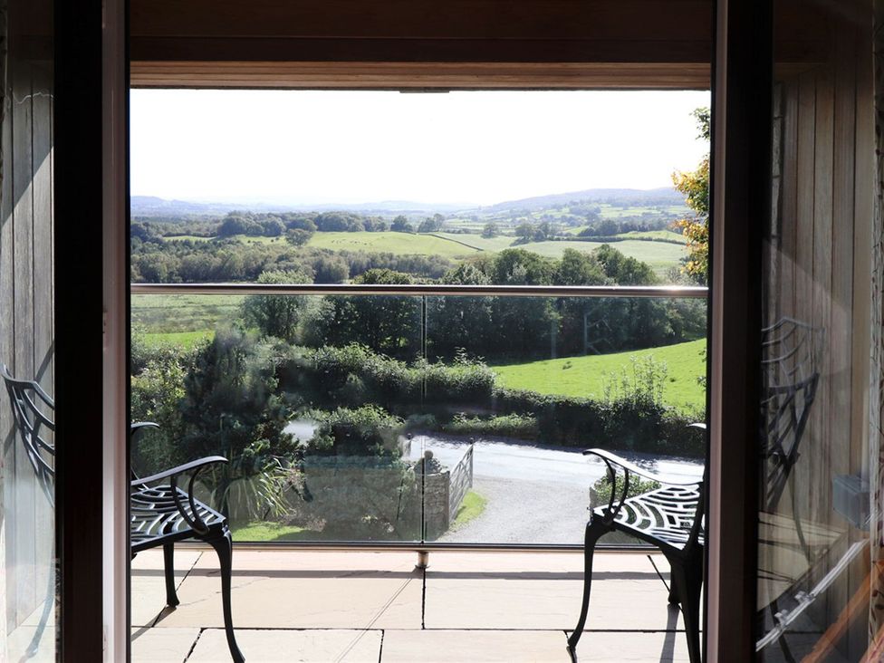 A balcony with chairs overlooking a landscape at High Beck in Kendal