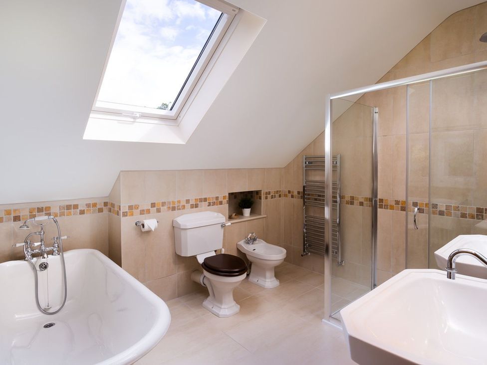 A bathroom with a bathtub, shower, and sink at High Beck, Kendal