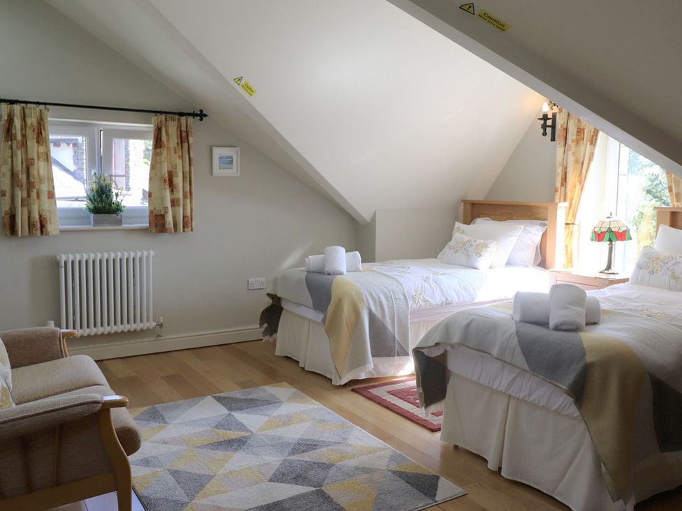 A bedroom with two beds and a chair at High Beck in Kendal