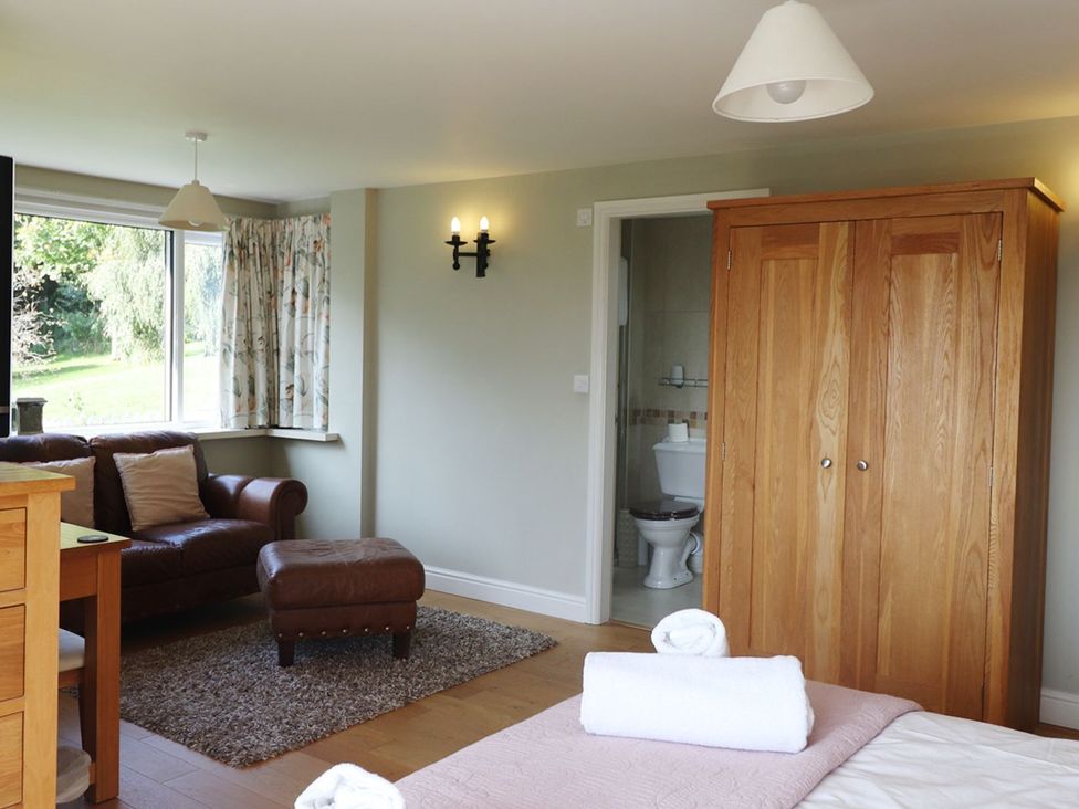 A bedroom with a sofa and wardrobe at High Beck in Kendal