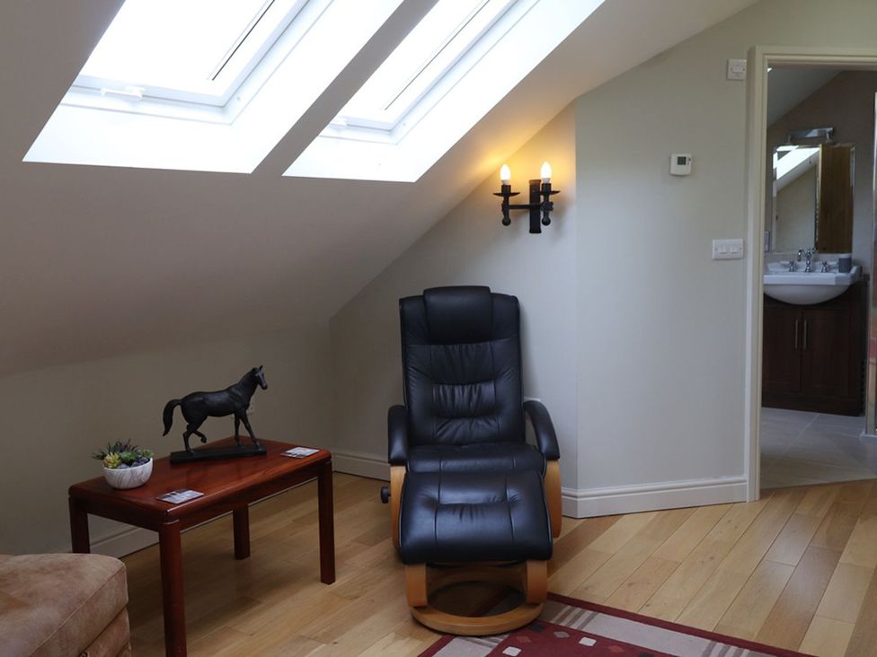 A loft with a chair and a small table at High Beck in Kendal