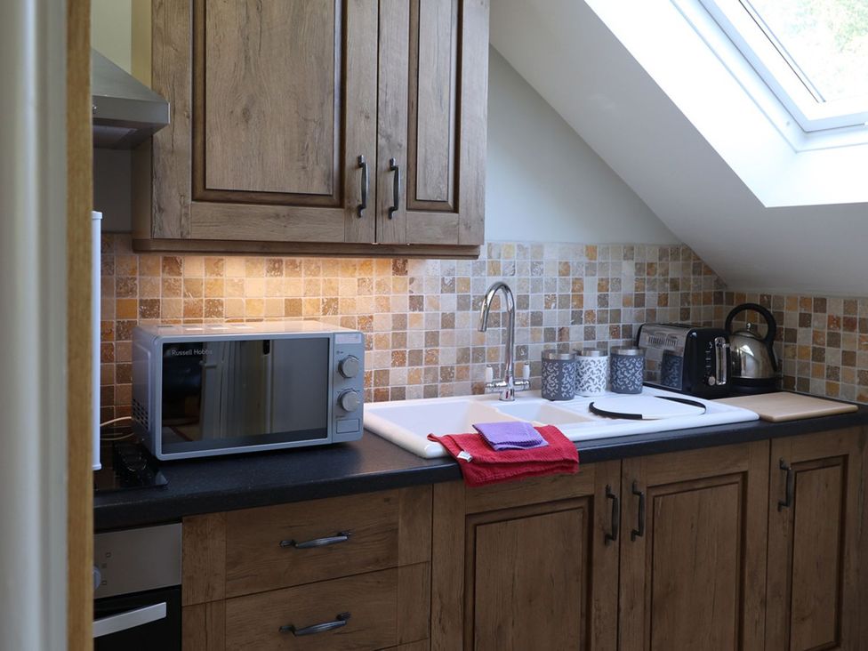 A kitchen with a microwave, sink, and kettle at High Beck in Kendal