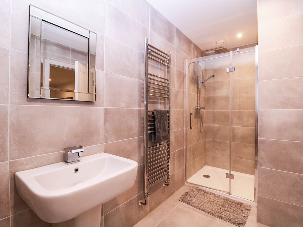 A bathroom with a sink, shower, and towel rail at Hanbury House in Lea