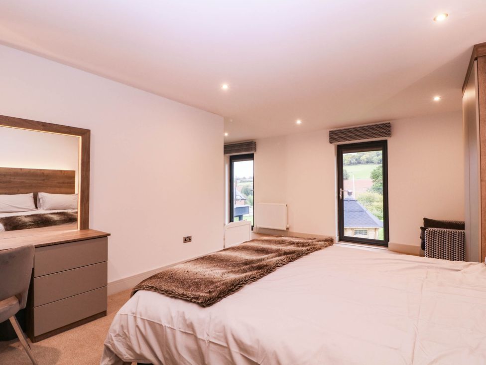 A bedroom with a bed, mirror, and dresser at Hanbury House in Lea