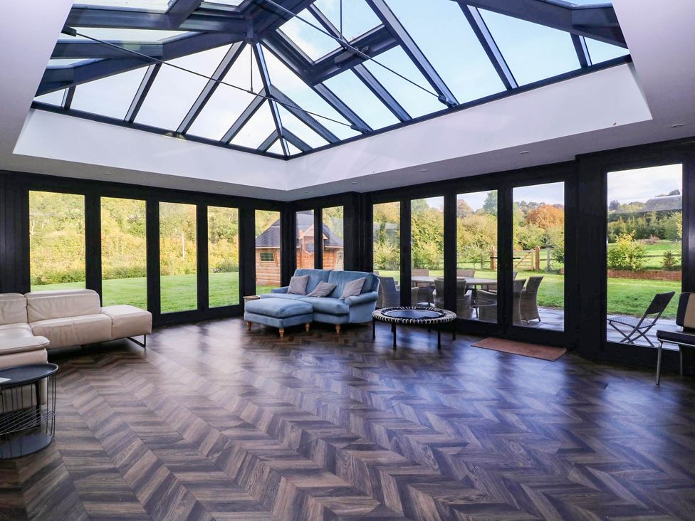 A conservatory with glass roof and outdoor furniture at Hanbury House in Lea