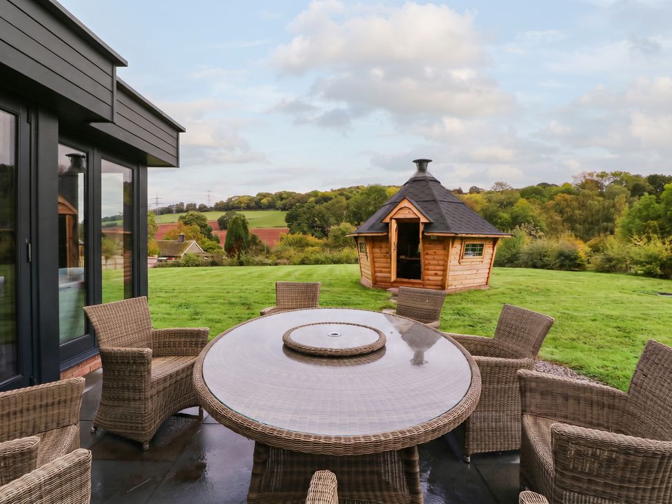 A table and chairs in an outdoor area with a wooden cabin at Hanbury House Lea