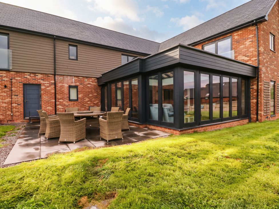 A garden with a patio area and a glass extension at Hanbury House, Lea