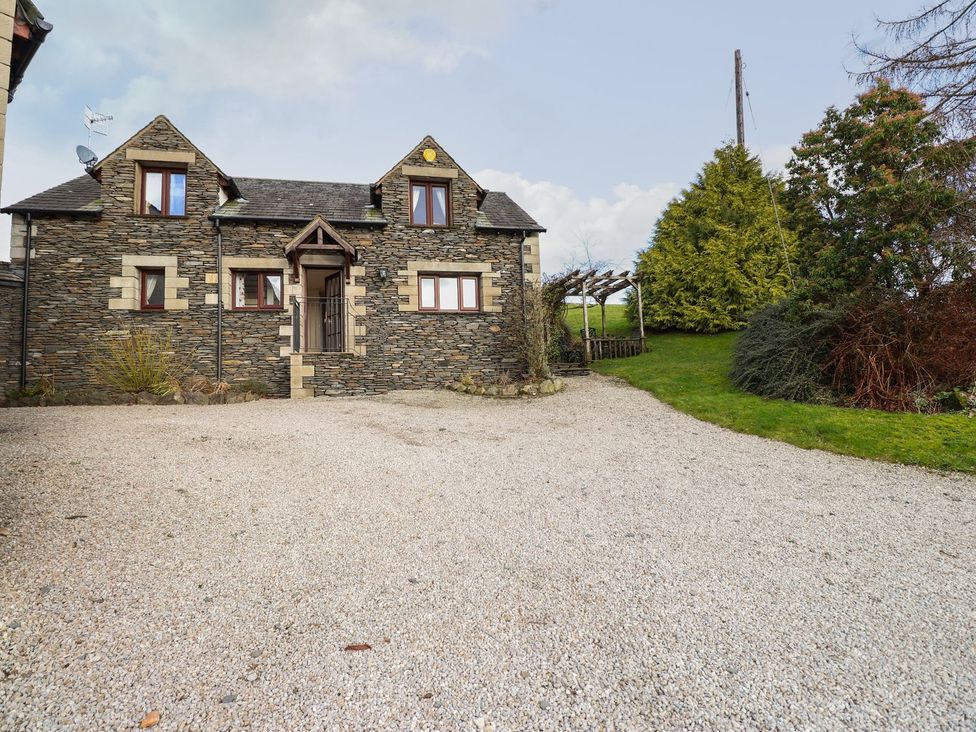 A house with a gravel driveway and garden at High Beck Cottage in Kendal
