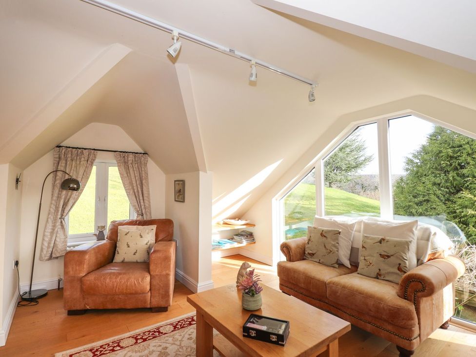 A snug with a sofa and chair beside a window at High Beck Cottage in Kendal
