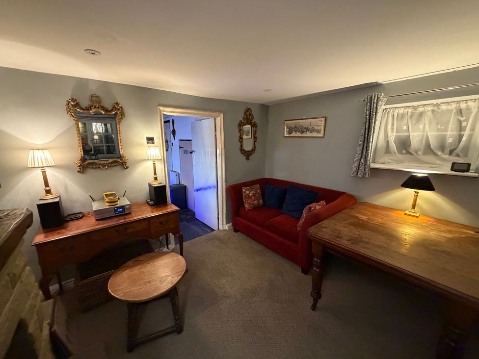 A living room with a sofa, table, and lamp at Rose Cottage in Brighton and Hove