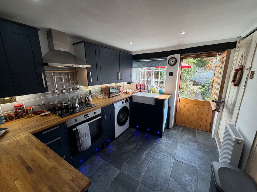 A kitchen with appliances and a door leading to the garden at Rose Cottage in Brighton and Hove