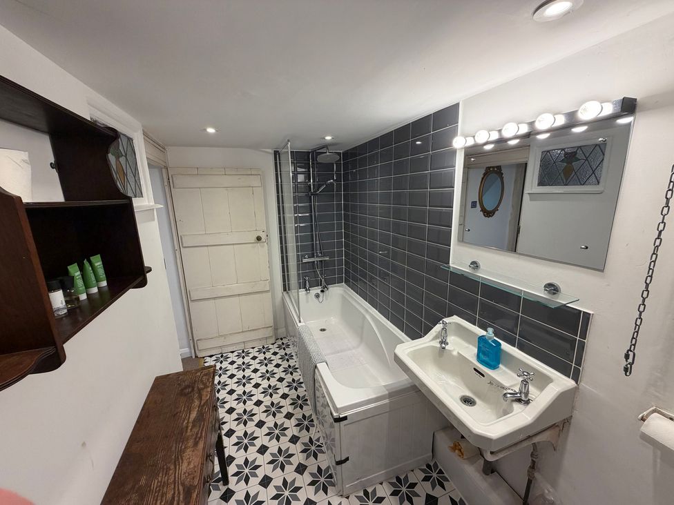 A bathroom featuring a bathtub, sink, and mirror at Rose Cottage in Brighton and Hove