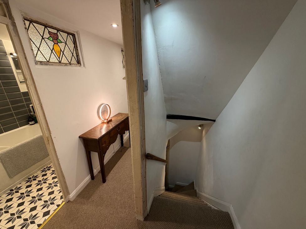A hallway with a table and light leading to a staircase at Rose Cottage in Brighton and Hove