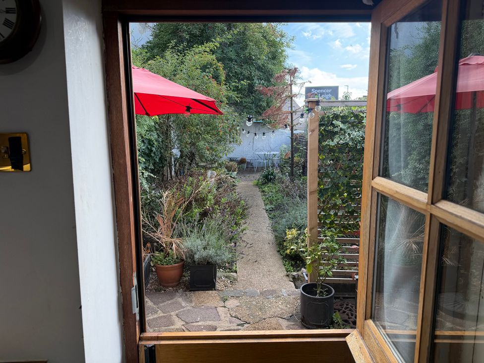 A garden with a pathway and red umbrellas at Rose Cottage in Brighton and Hove
