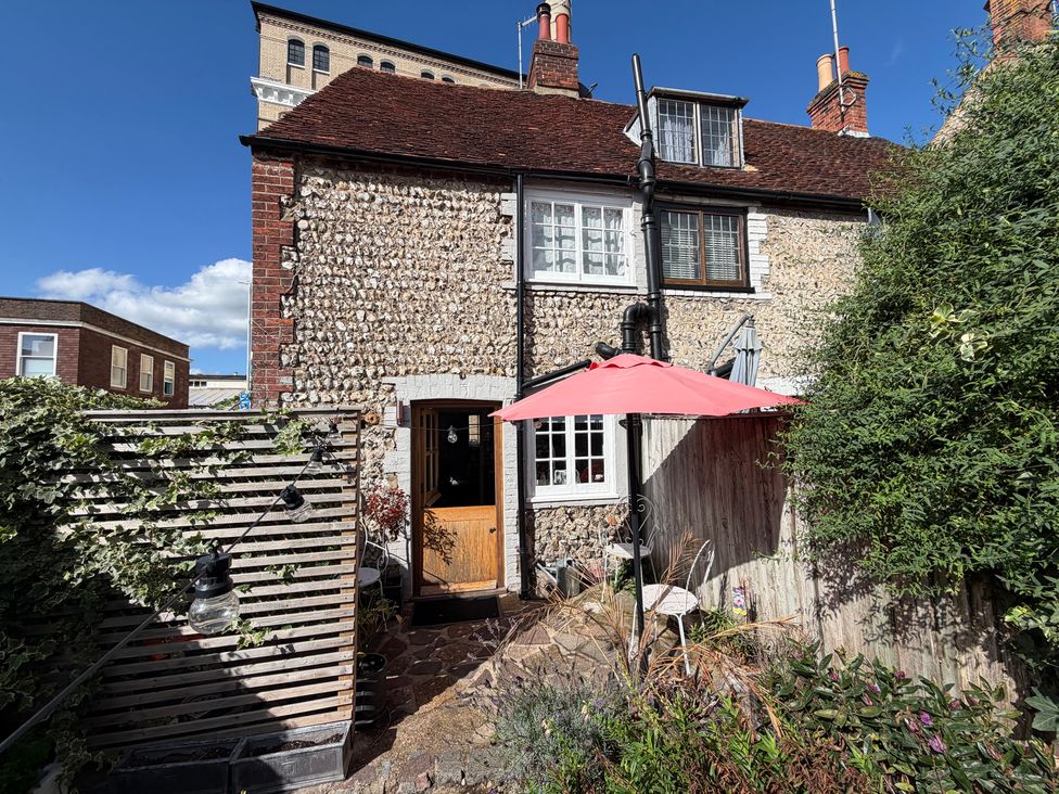 A garden with a house, door, umbrella, and plants at Rose Cottage in Brighton and Hove