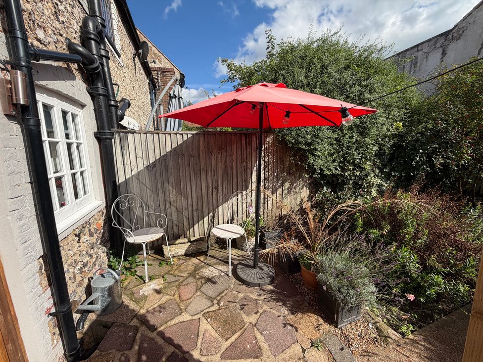 A garden area with a table and chairs under an umbrella at Rose Cottage in Brighton and Hove