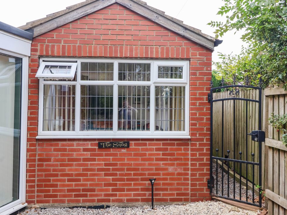 An outdoor view of The Snug with a brick wall and gate