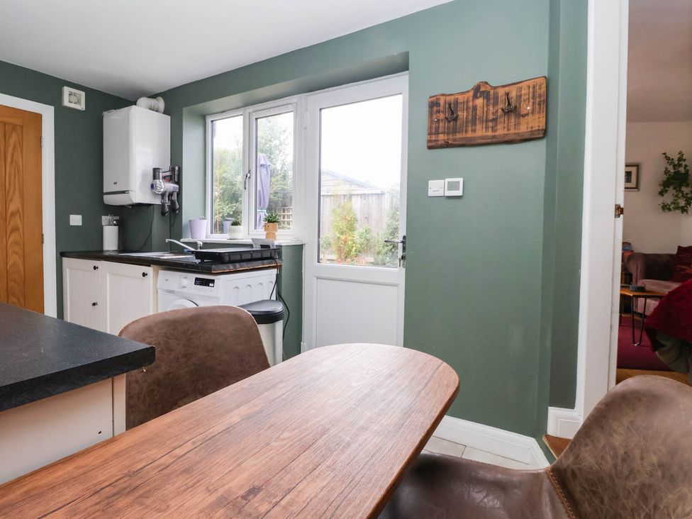 A kitchen with a table and chairs and a washing machine at The Snug 