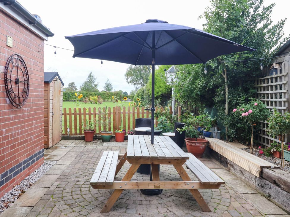 A garden with a picnic table under an umbrella at The Snug