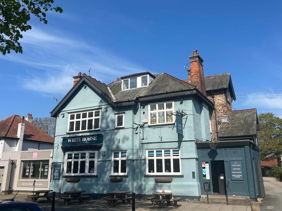 A pub exterior with a sign and parking area at The Snug Upper Poppleton
