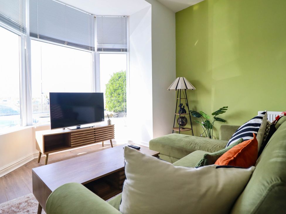 A living room with a green sofa and television at Flat 1 Greenfields Barmouth