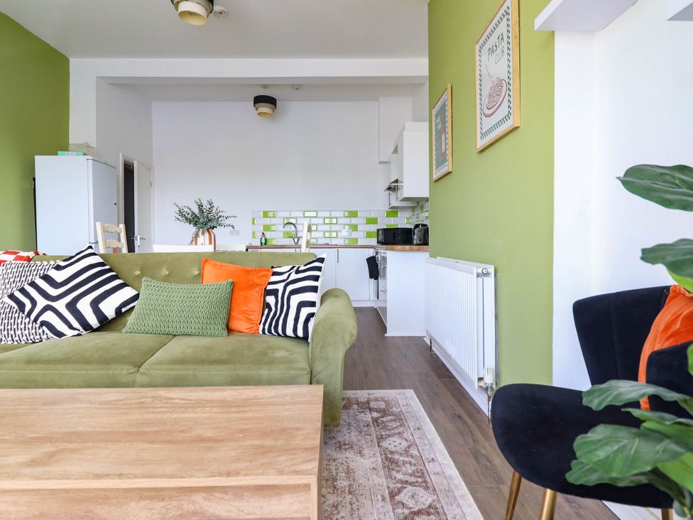 A living room with a sofa and kitchen area at Flat 1 Greenfields Barmouth