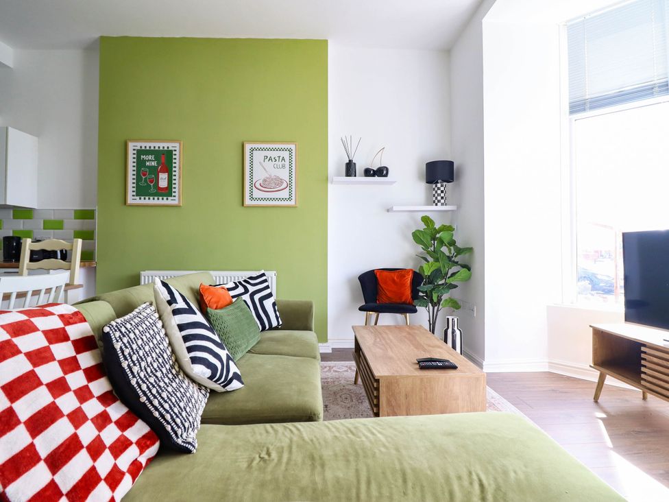 A living room with a green wall and seating area at Flat 1 Greenfields in Barmouth