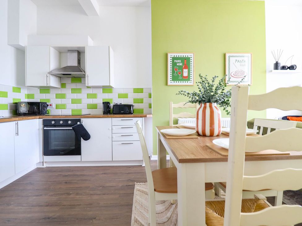 A kitchen with appliances and a dining table at Flat 1 Greenfields in Barmouth