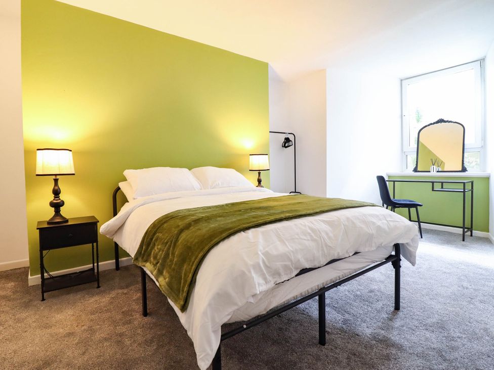 A bedroom with a bed and a desk at Flat 1 Greenfields in Barmouth