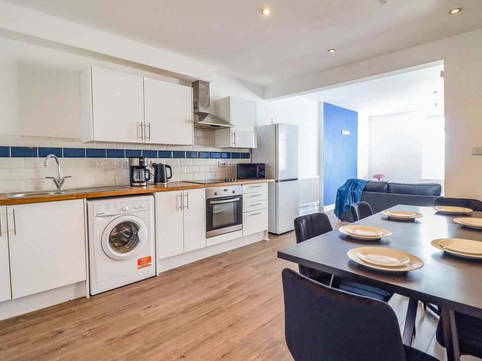 A kitchen with appliances and dining table at Flat 4 Greenfields Barmouth