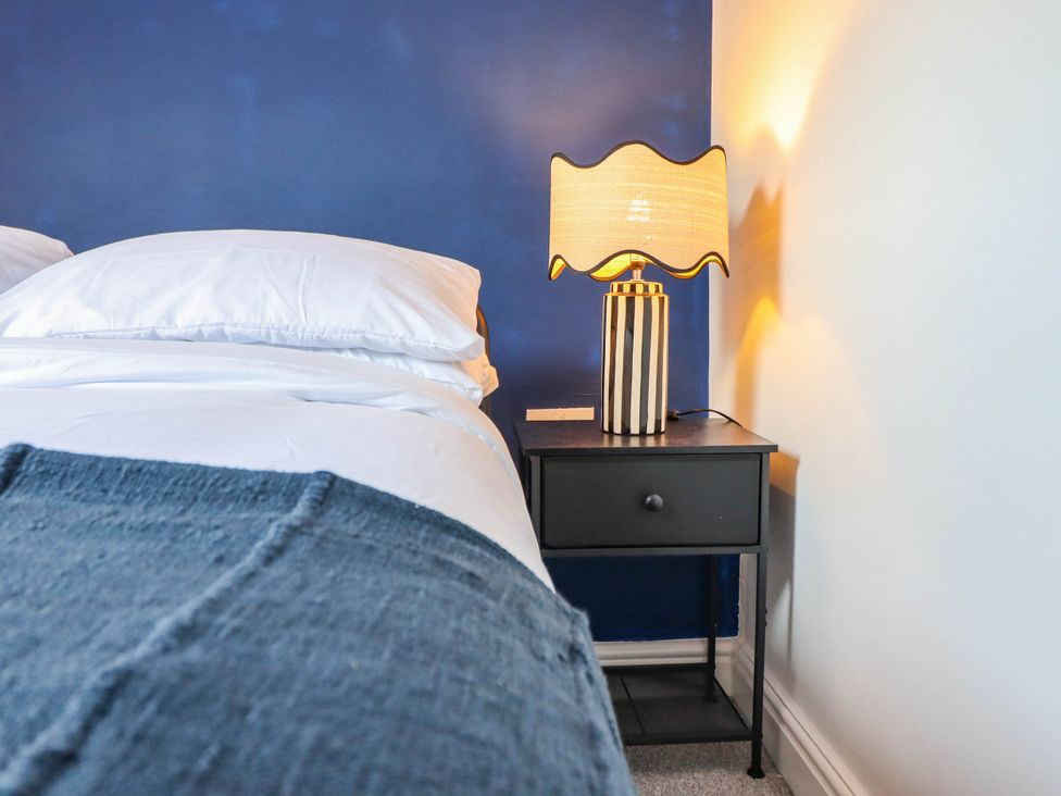 A bedroom with a bed and a lamp on a nightstand at Flat 4 Greenfields in Barmouth