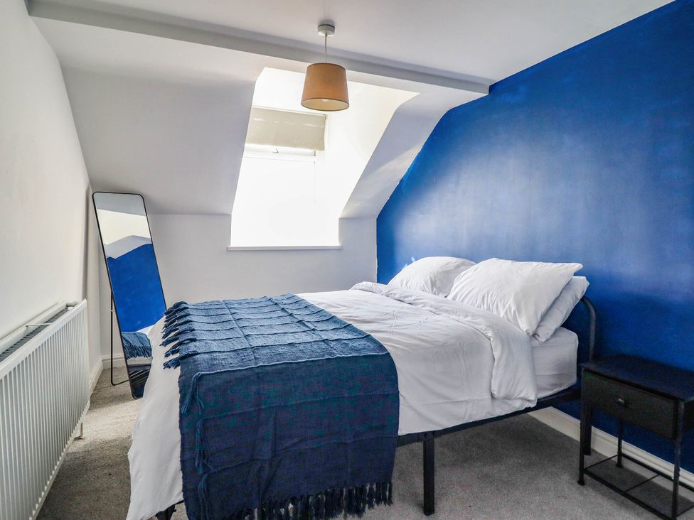 A bedroom with a bed and mirror at Flat 4 Greenfields in Barmouth