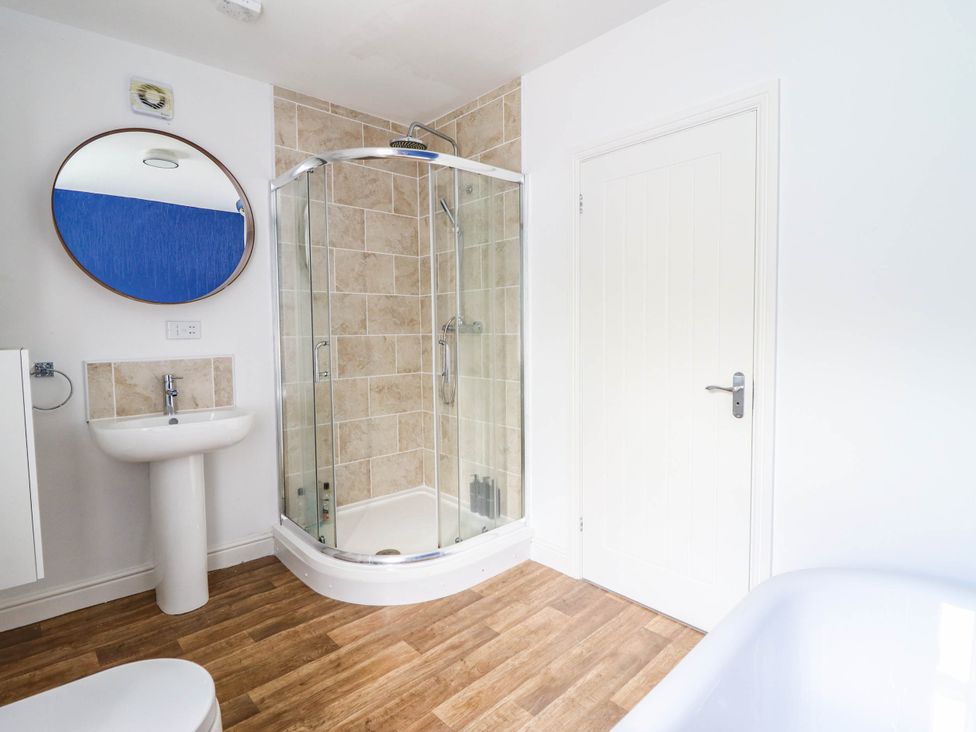 A bathroom with a shower, sink and a mirror at Flat 4 Greenfields Barmouth