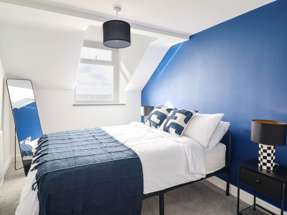 A bedroom with a bed and mirror at Flat 4 Greenfields Barmouth