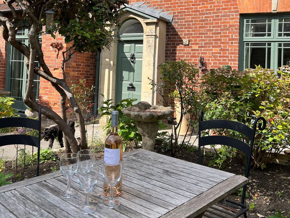 A garden with a table and wine bottle at Kylemore in Glastonbury