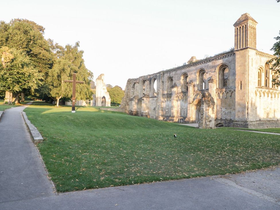 An outdoor view of ruins and a cross with trees at Kylemore in Glastonbury