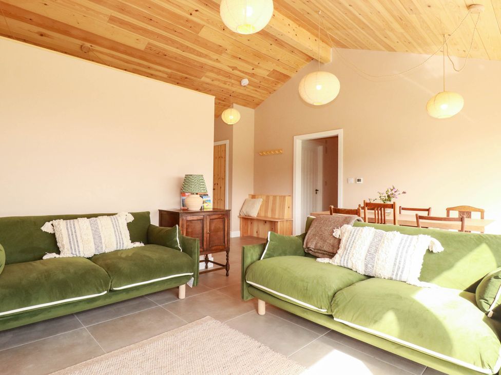 A living room with green sofas and a dining area at Granfer’s