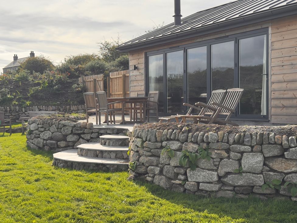 An outdoor area with a stone wall and furniture at Granfer’s near Penryn