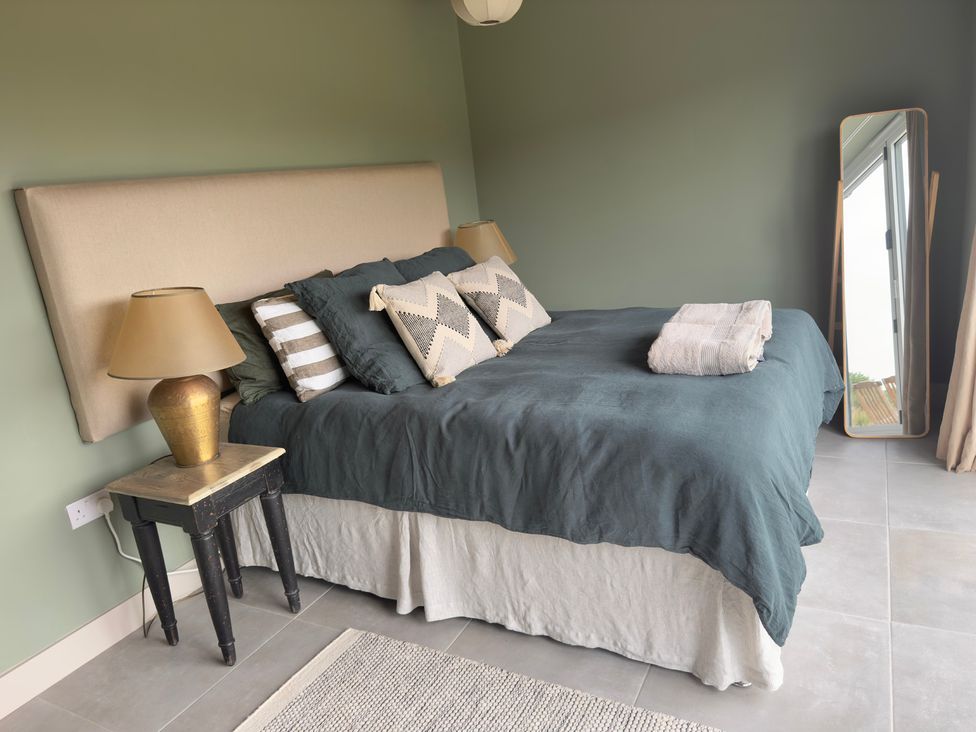 A bedroom with a bed and a large mirror at Granfer’s near Penryn