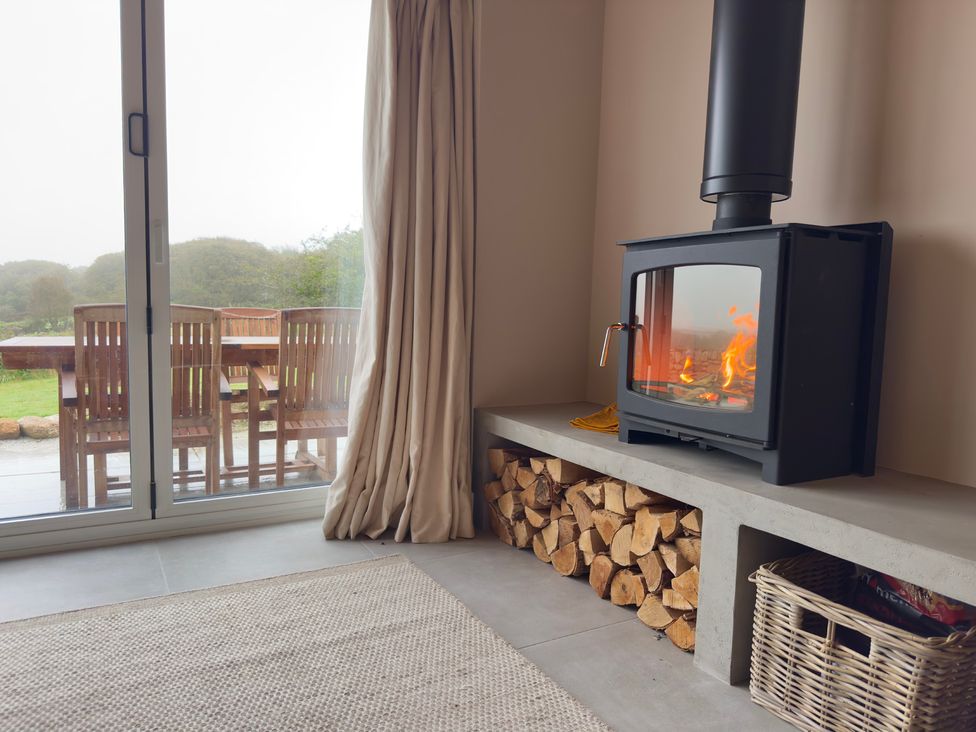 A living room with a fireplace and sliding door to the outside at Granfer’s near Penryn
