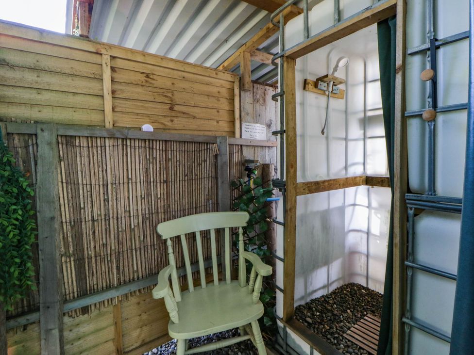 An outdoor shower with a chair and wooden walls at Bell Tent in Builth Wells