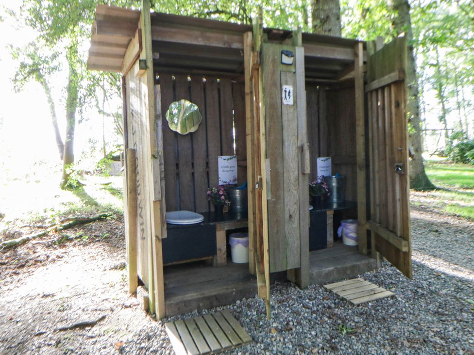 An outdoor bathroom with wooden stalls and basic fixtures at Bell Tent Builth Wells