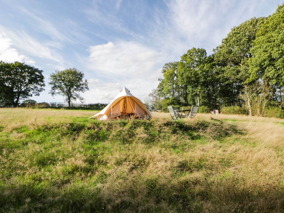 A tent with a table and chairs on a grassy area at Bell Tent in Builth Wells