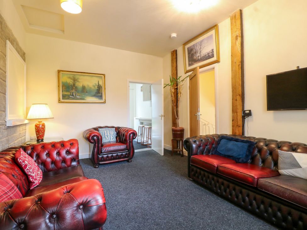A living room with leather sofas and artwork at Greystones Apartment A near Buxton