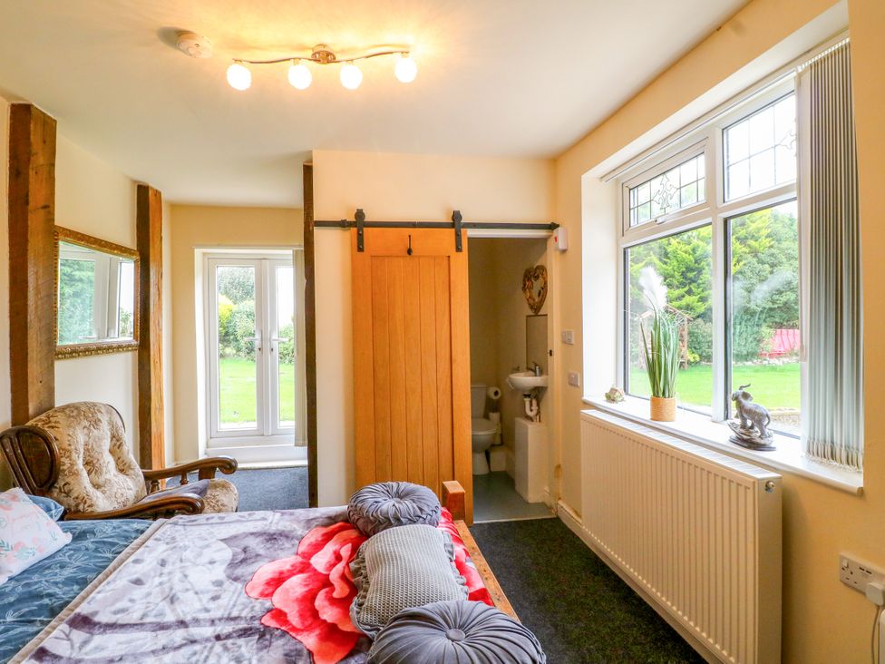 A bedroom with a bed, window, and sliding door at Greystones Apartment A near Buxton