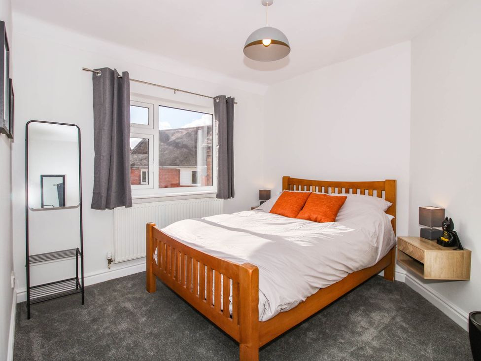 A bedroom with a bed and mirror at 3 Jubilee Cottages in Pontesbury