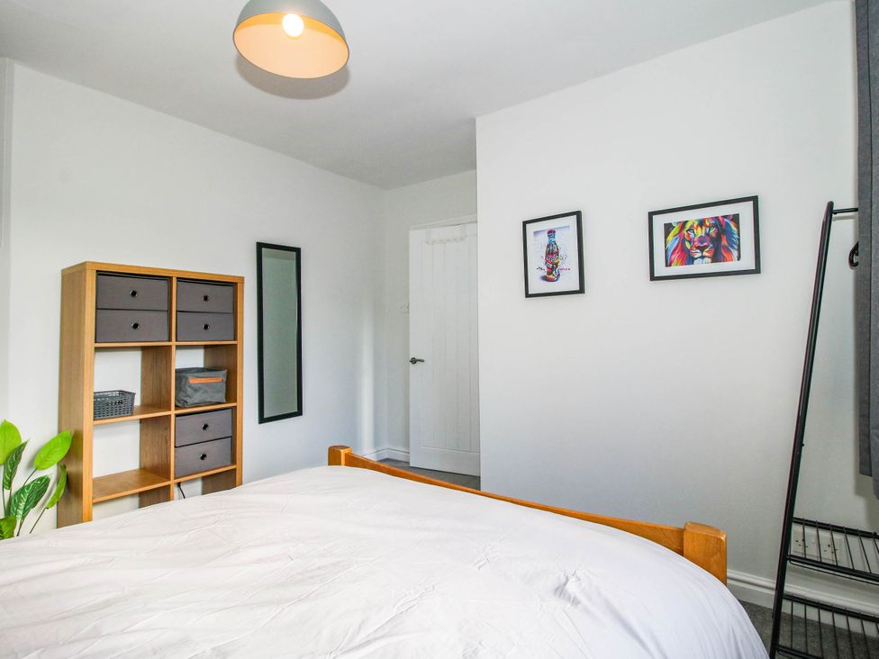 A bedroom with a bed and shelves at 3 Jubilee Cottages Pontesbury