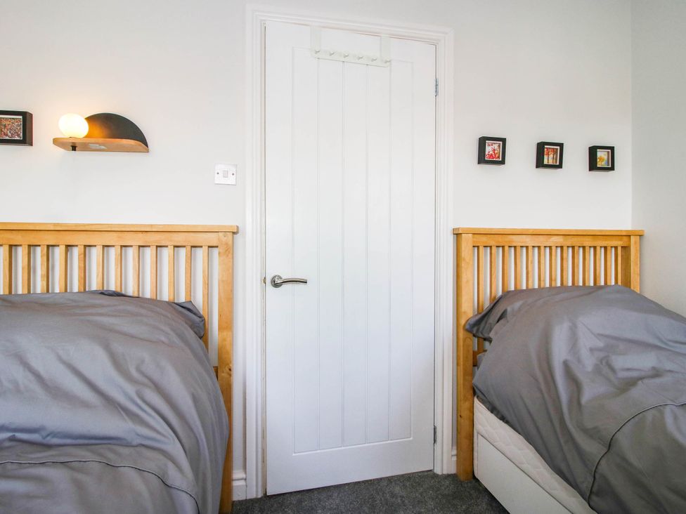 A bedroom with two beds and a door at 3 Jubilee Cottages Pontesbury